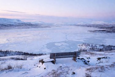 High tundra bench overlooking the vast frozen sheet of Lake Torneträsk in Swedish Lapland