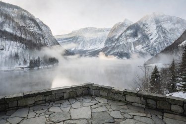 Raised stone terrace looking out over Hallstätter See with mist and snowy alpine slopes