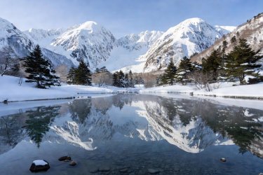 Taisho Pond in Kamikochi with the snow-covered peaks of Mount Hotaka reflecting in clear water