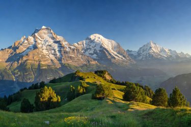 Expansive view of the Eiger, Monch, and Jungfrau peaks from a high Swiss ridge